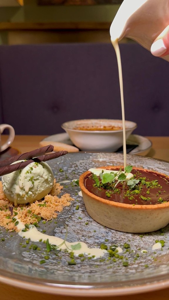 A decadent extra bitter chocolate tart served with a scoop of creamy pistachio ice cream.