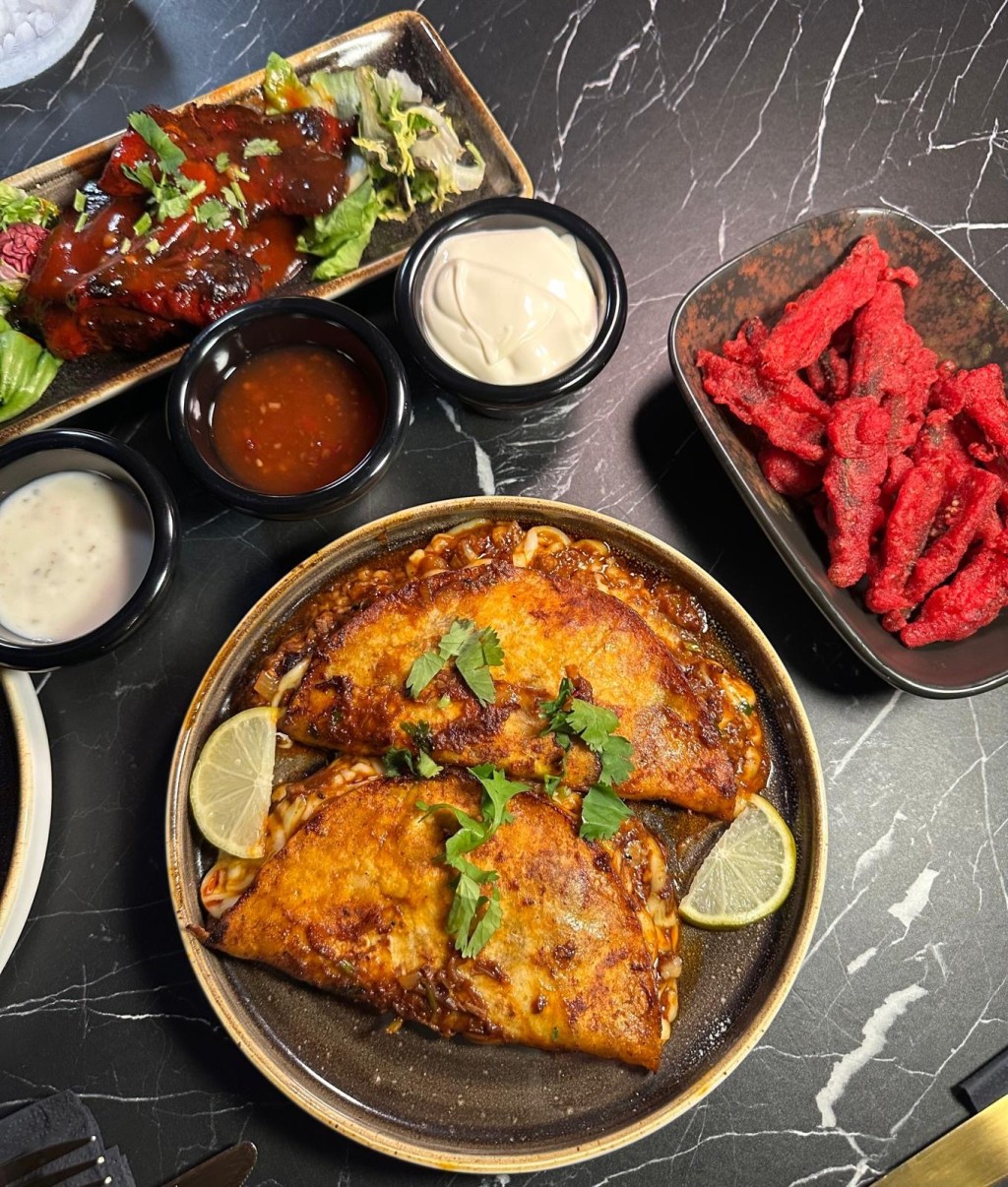 A spread of small plates from The Chamber South Shields, featuring bao buns, birria tacos, sushi rolls, lamb chops, kebabs, and crispy okra fries.