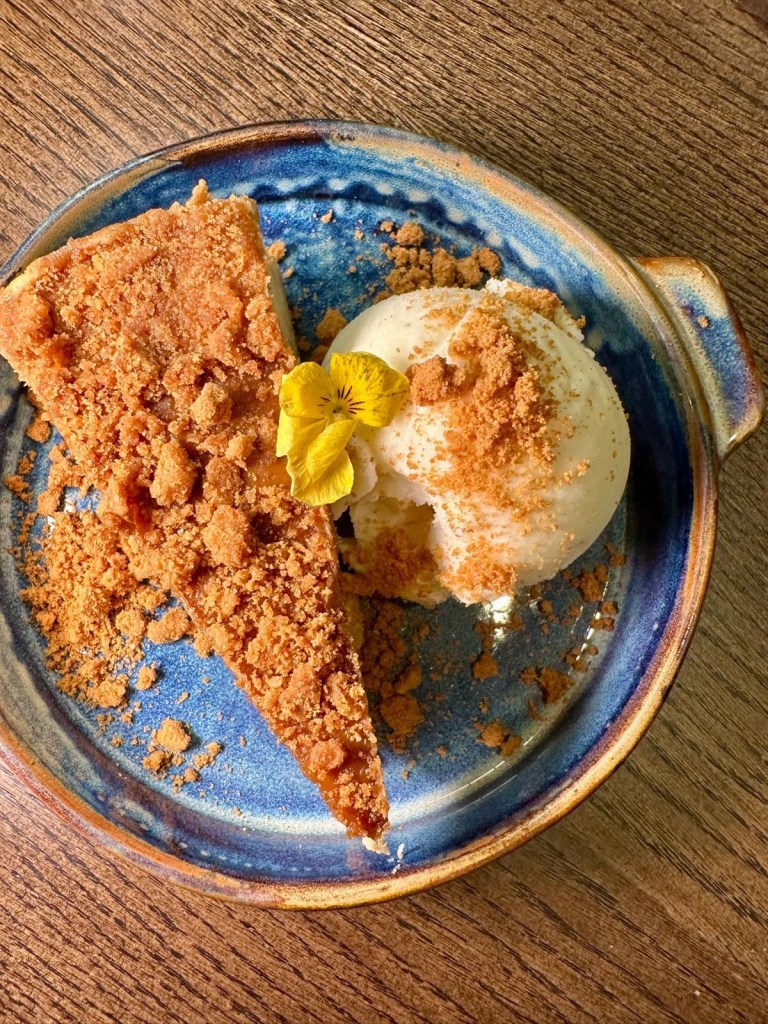 A beautifully plated slice of cheesecake with a smooth, creamy texture, garnished with fresh berries and a drizzle of sauce.