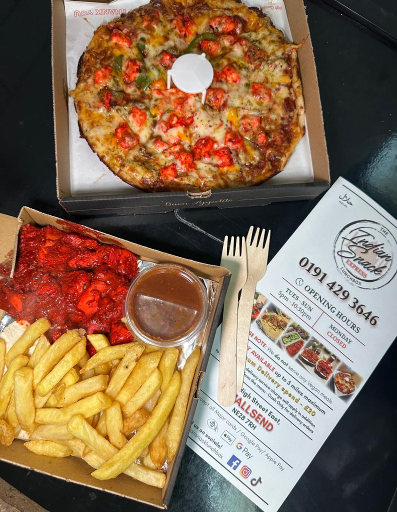 A delicious meal featuring a golden crust pizza topped with red chicken pieces and melted cheese, served alongside a portion of crispy fries and a small container of sauce.