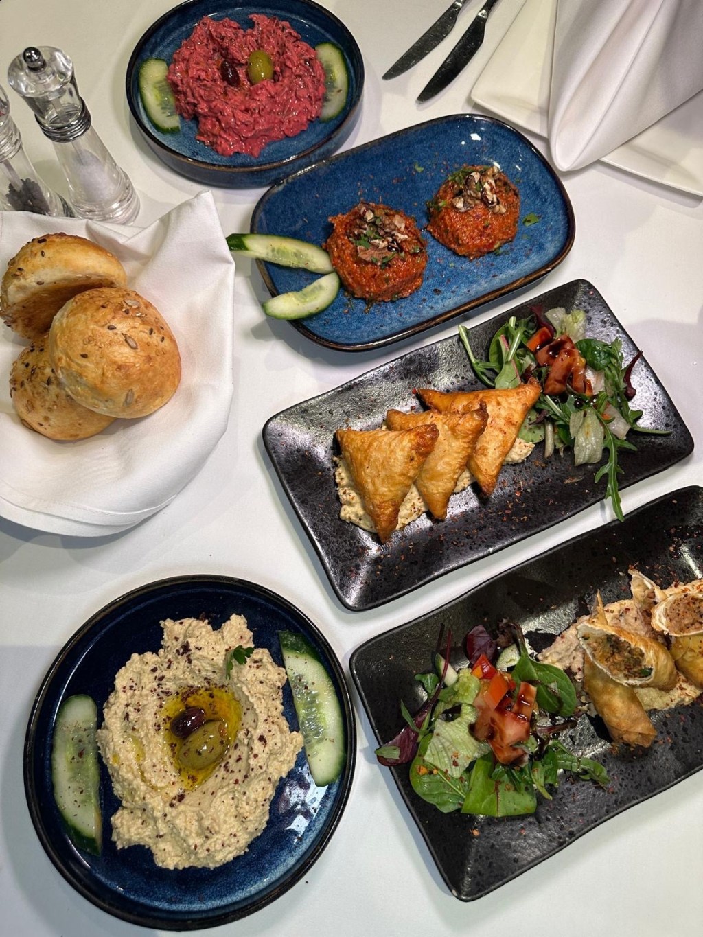 A selection of Turkish mezze starters at Turknaz Restaurant, featuring hummus, kisir, muska boregi, avci boregi, pancar salatasi, and freshly baked bread buns.