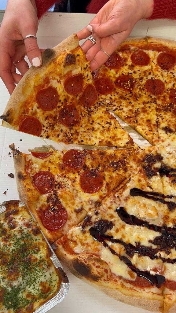 A large 20-inch New York-style pizza, half topped with spicy pepperoni and honey drizzle, and half with creamy goat’s cheese and red onion jam, served on a thin, crispy crust.