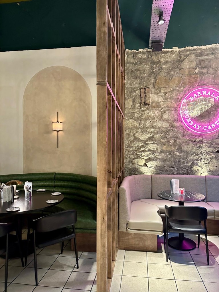 A stylish dining booth with plush seating, moody lighting, and elegant decor at Dakwala Bombay Canteen.