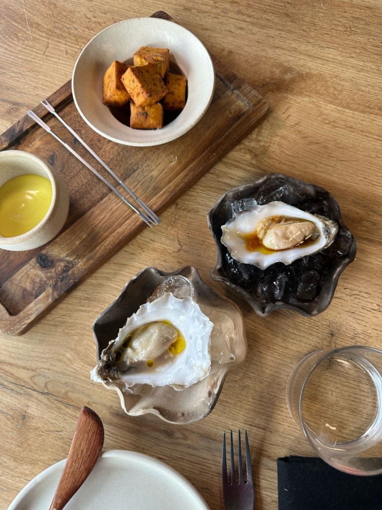 Freshly shucked oysters on a bed of ice, drizzled with ponzu and orange oil, garnished with microgreens.