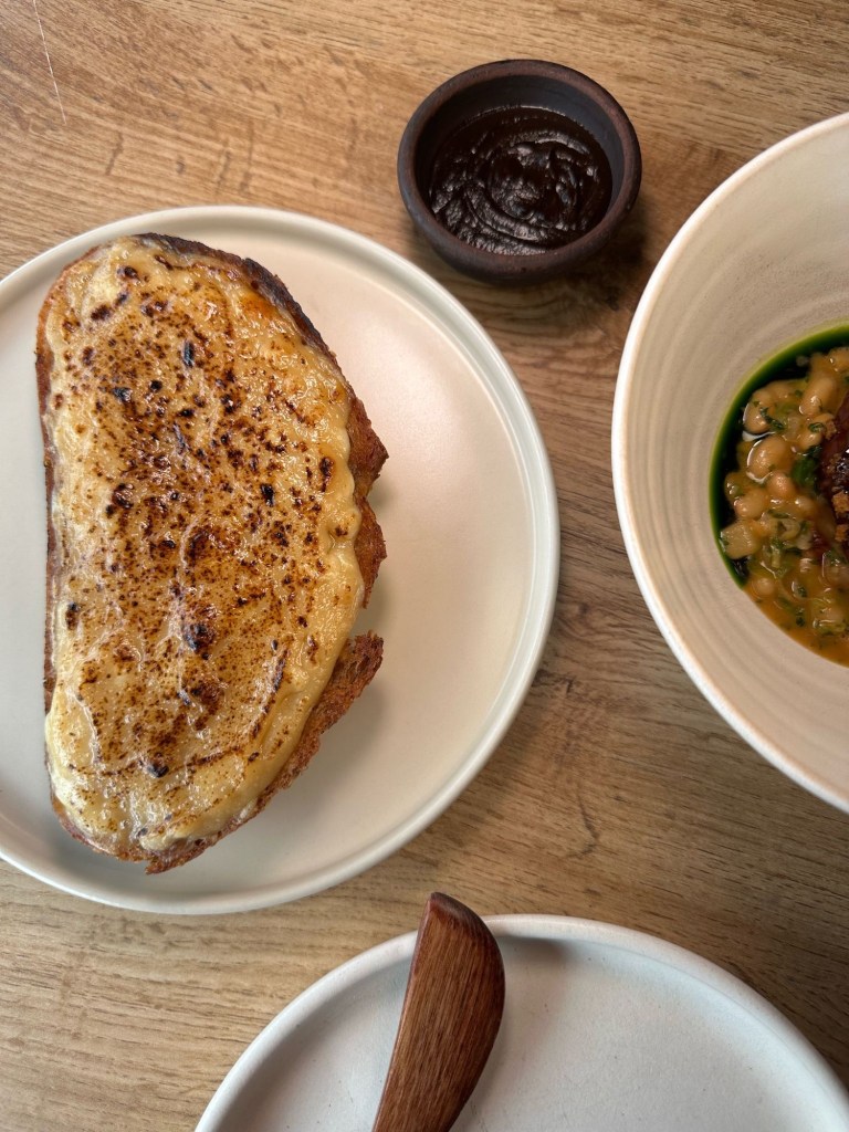 Golden, cheesy Welsh rarebit on toasted sourdough with a side of glossy black garlic ketchup.