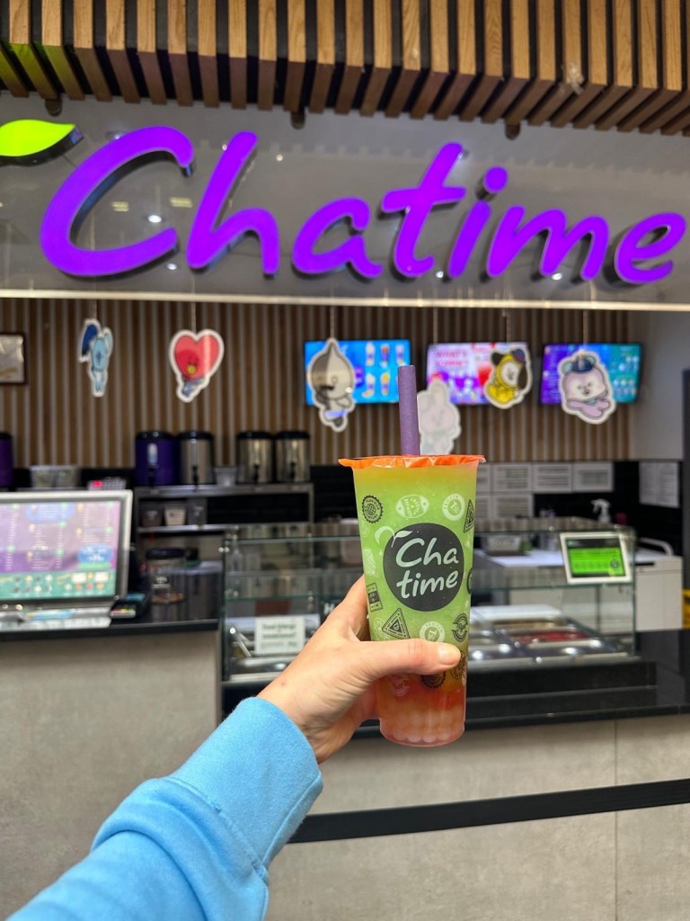 Two Chatime bubble teas, one matcha-flavored and one brown sugar, served in plastic cups with wide straws for tapioca pearls.
