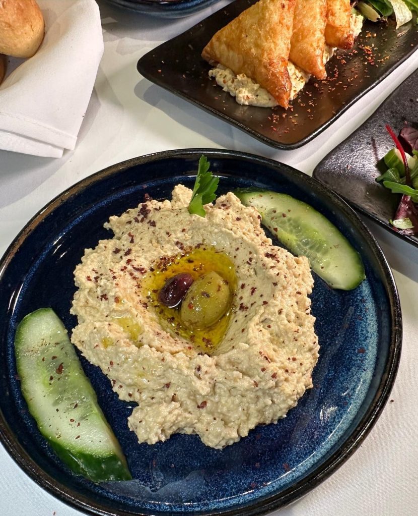 A creamy bowl of hummus drizzled with olive oil and garnished with whole chickpeas, served at Turknaz Restaurant.
