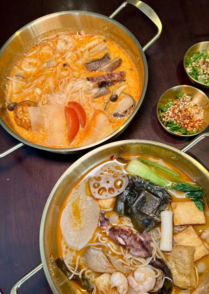 A steaming bowl of Malatang broth filled with fresh seafood, mushrooms, and Asian greens, garnished with coriander, crushed peanuts, and red chili.