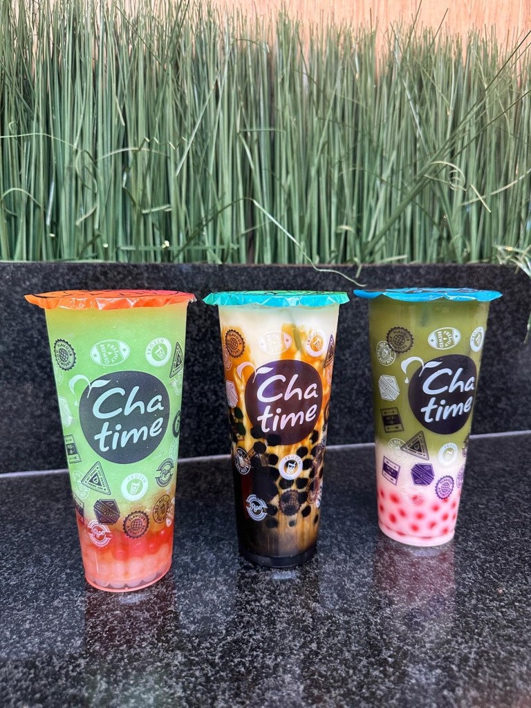 Two Chatime bubble teas, one matcha-flavored and one brown sugar, served in plastic cups with wide straws for tapioca pearls.
