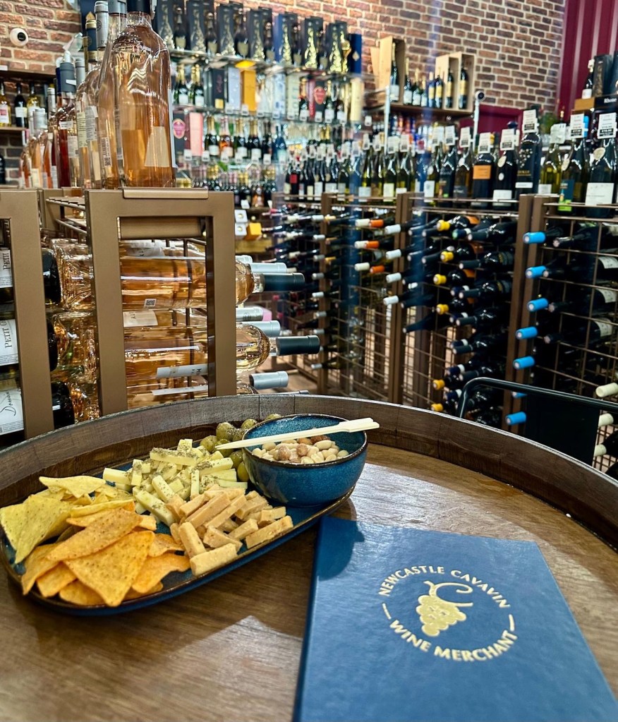 A delicious snack platter at Newcastle Cavavin featuring olives, cheese, nuts, and crisps, served alongside glasses of wine.