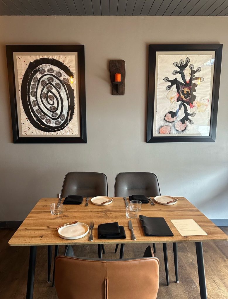 A modern yet cozy dining space with warm lighting, rustic wooden tables, and open kitchen views.