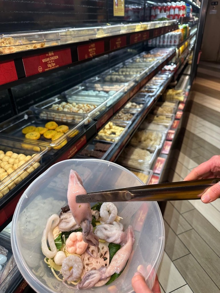 A colorful bowl filled with fresh seafood, vegetables, and noodles, ready to be cooked in a custom Malatang broth.