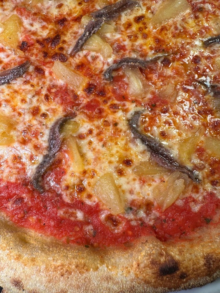 A bold anchovies and pineapple pizza with a crispy crust at Pizza Punks.