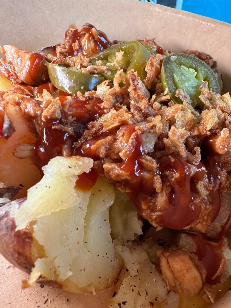 The BBQ Banger baked potato at Spud Life Newcastle, featuring pulled chicken in smoky BBQ sauce, crispy onions, and fresh herbs.