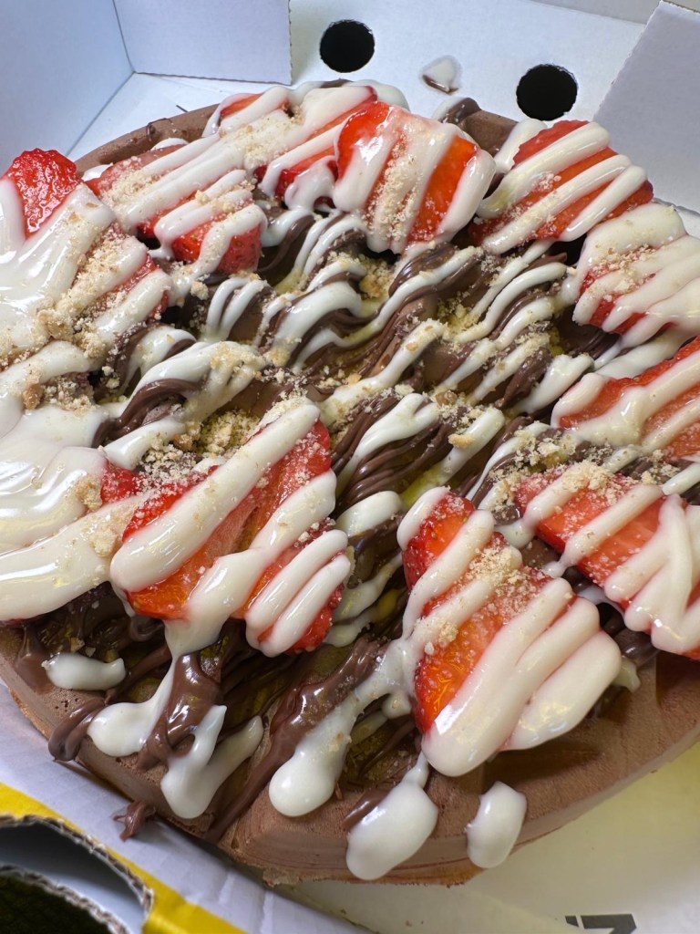 Fluffy waffle topped with fresh strawberries, melted chocolate, and syrup at Shakedown Jesmond.