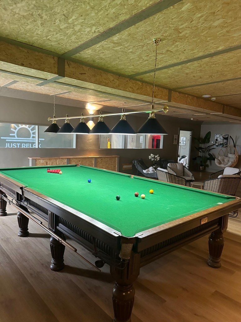 Snooker table with soft, cosy lounge seating in the background at High Hill Stay leisure suite.