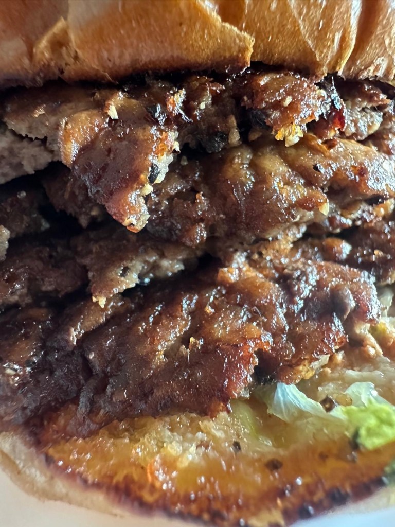 Four stacked smash burger patties with melted cheese and signature sauce from Shakedown Jesmond.