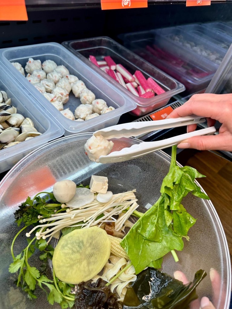 Custom Malatang bowl with fresh seafood, vegetables, and noodles from ingredient fridges