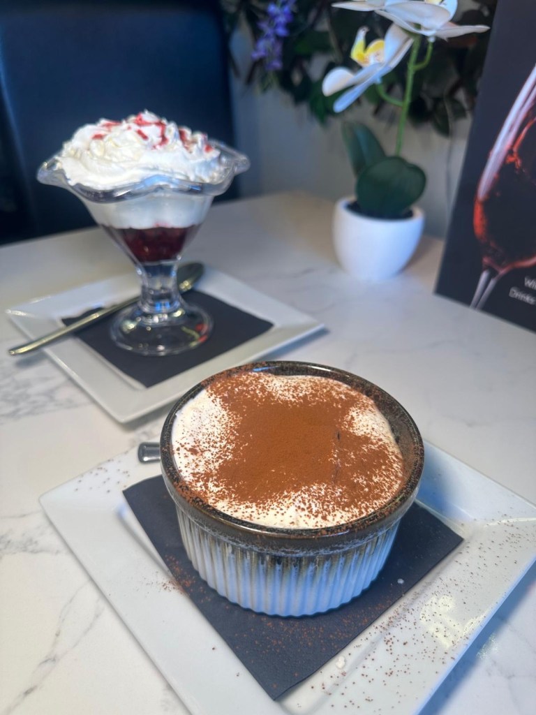 Tiramisu and Eton mess desserts in front of Da-Zero neon sign