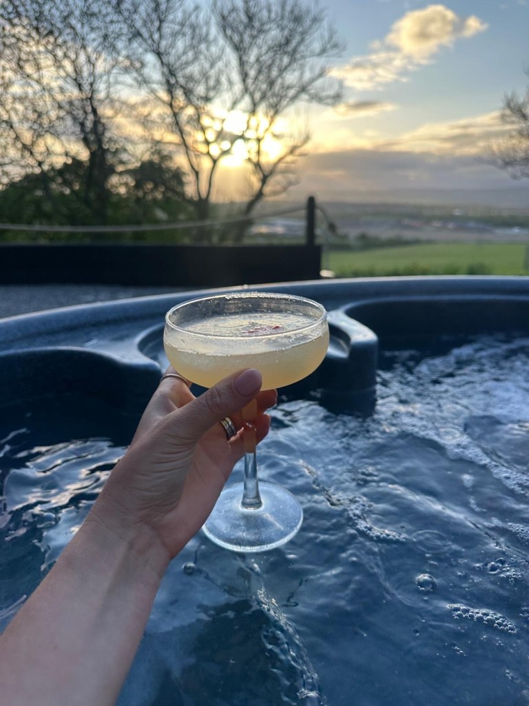 Colourful cocktail resting on the edge of a bubbling hot tub at High Hill Stay lodge.