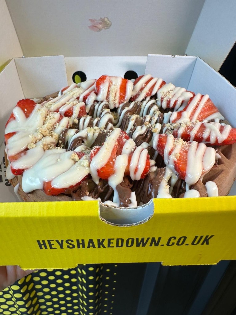 Fluffy waffle topped with fresh strawberries, melted chocolate, and syrup at Shakedown Jesmond.