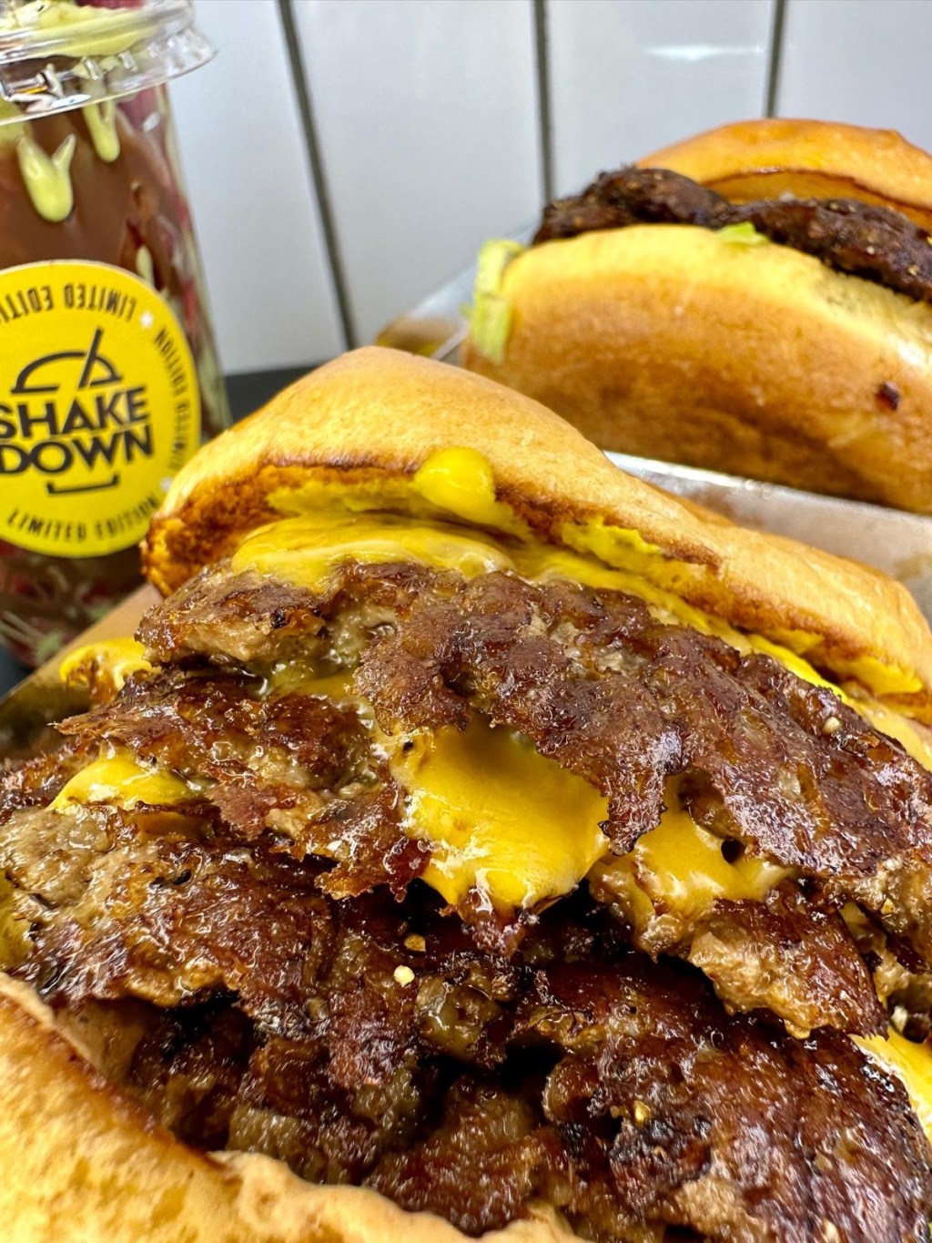 Close-up of juicy smash burger with melted cheese and toppings at Shakedown Jesmond