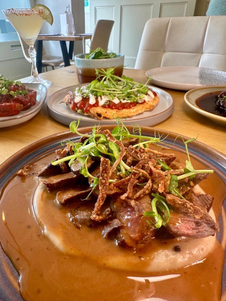 Sliced rump steak with celeriac purée, peppercorn sauce, and crispy onions from Isla Durham.