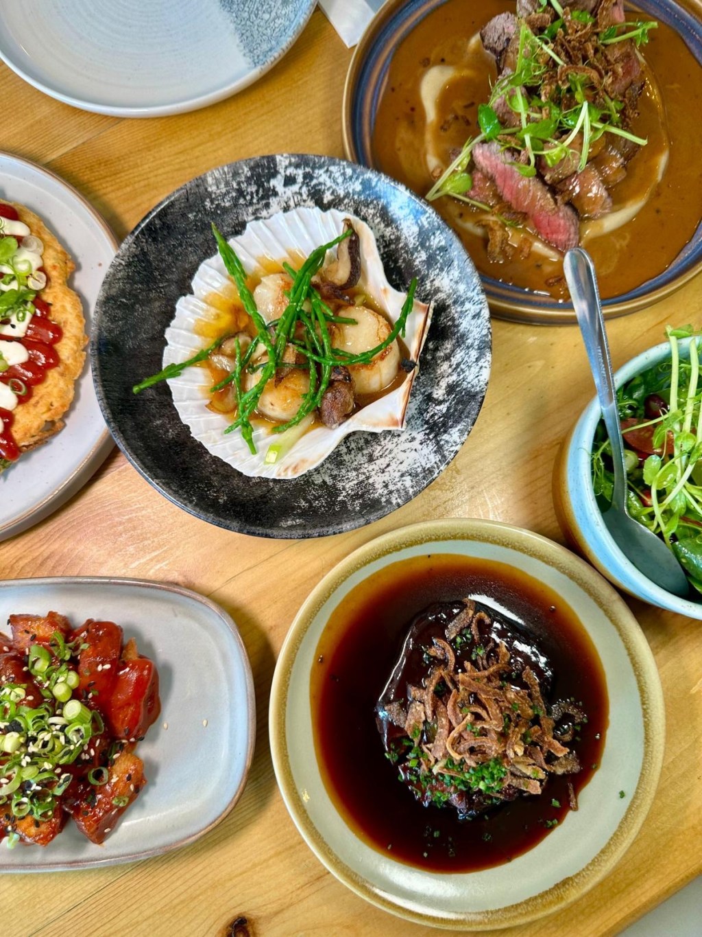 Selection of small plate mains at Isla Durham including scallops, rump steak, pork belly, slow-cooked beef, Japanese pancake, and seasonal salad.