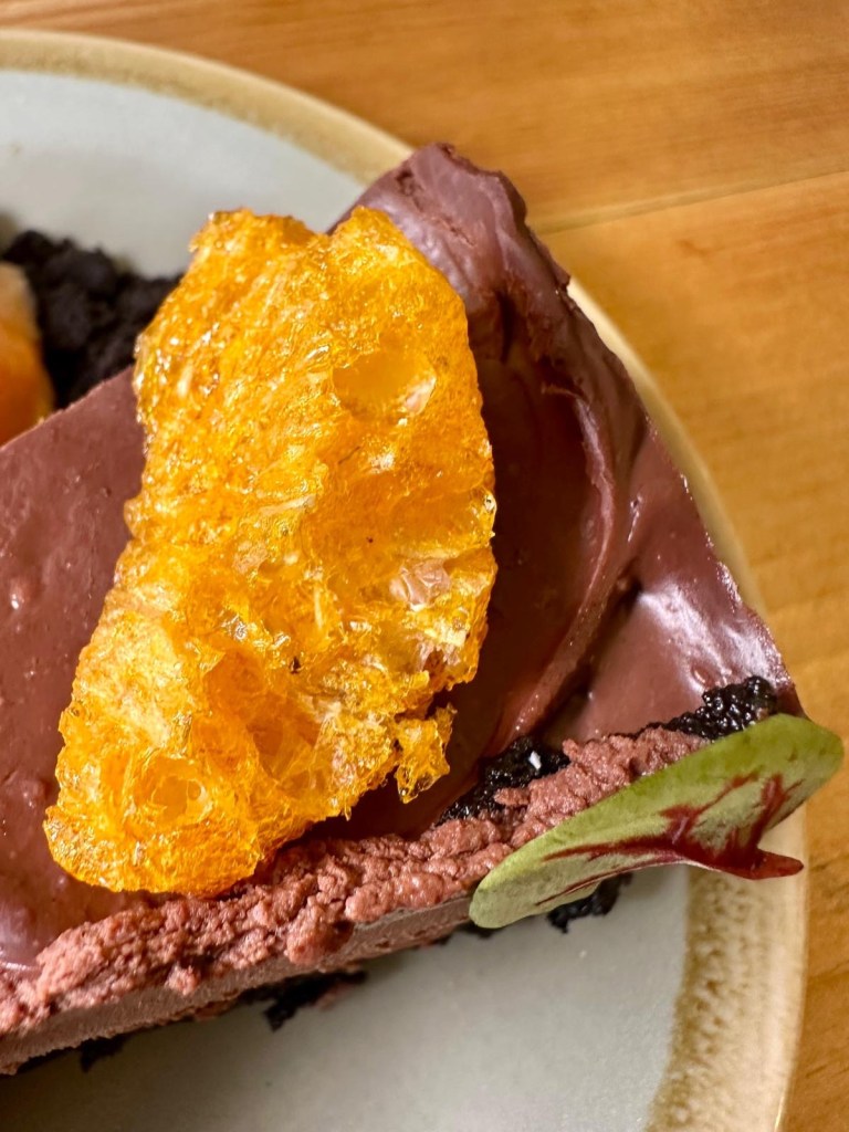 Close-up of dehydrated mandarin garnish on Oreo torte dessert at Isla in Durham.