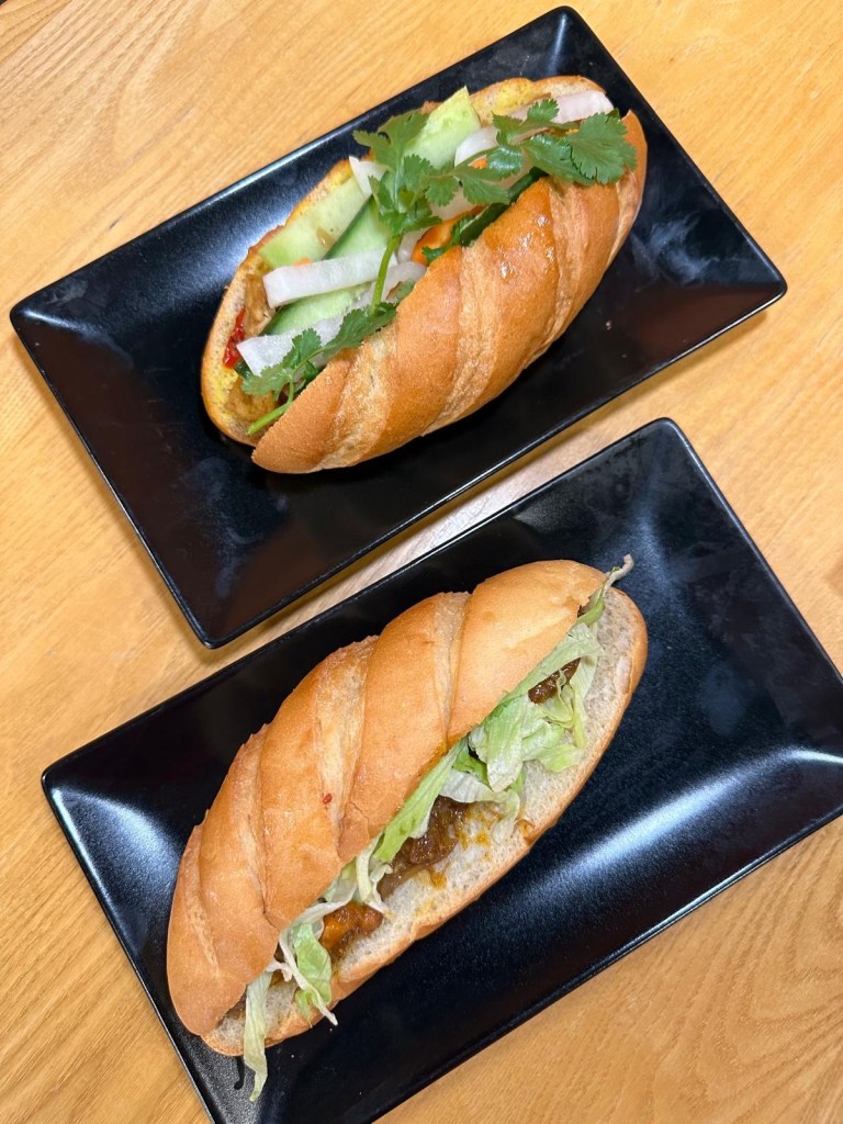 Two Vietnamese bánh mì sandwiches from Ngon Bánh Mì Newcastle, one filled with slow-cooked beef stew and the other with fragrant curry chicken.