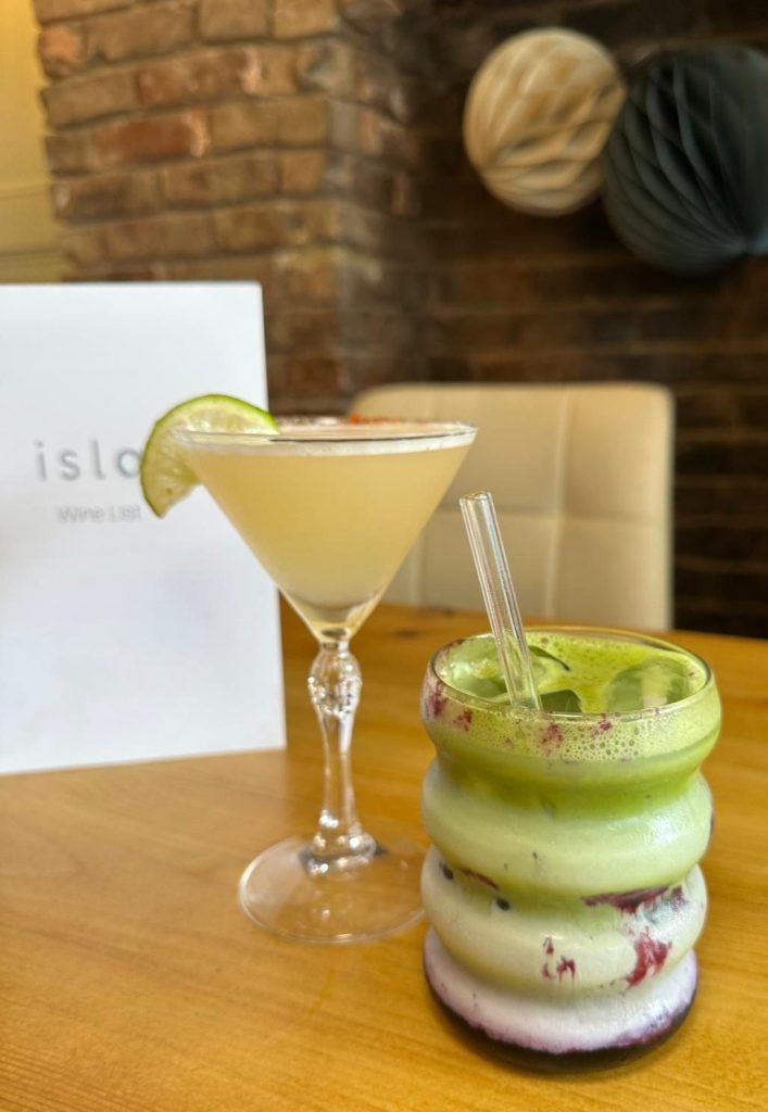 Blueberry iced matcha latte and smoky mezcal margarita served side by side at Isla in Durham.