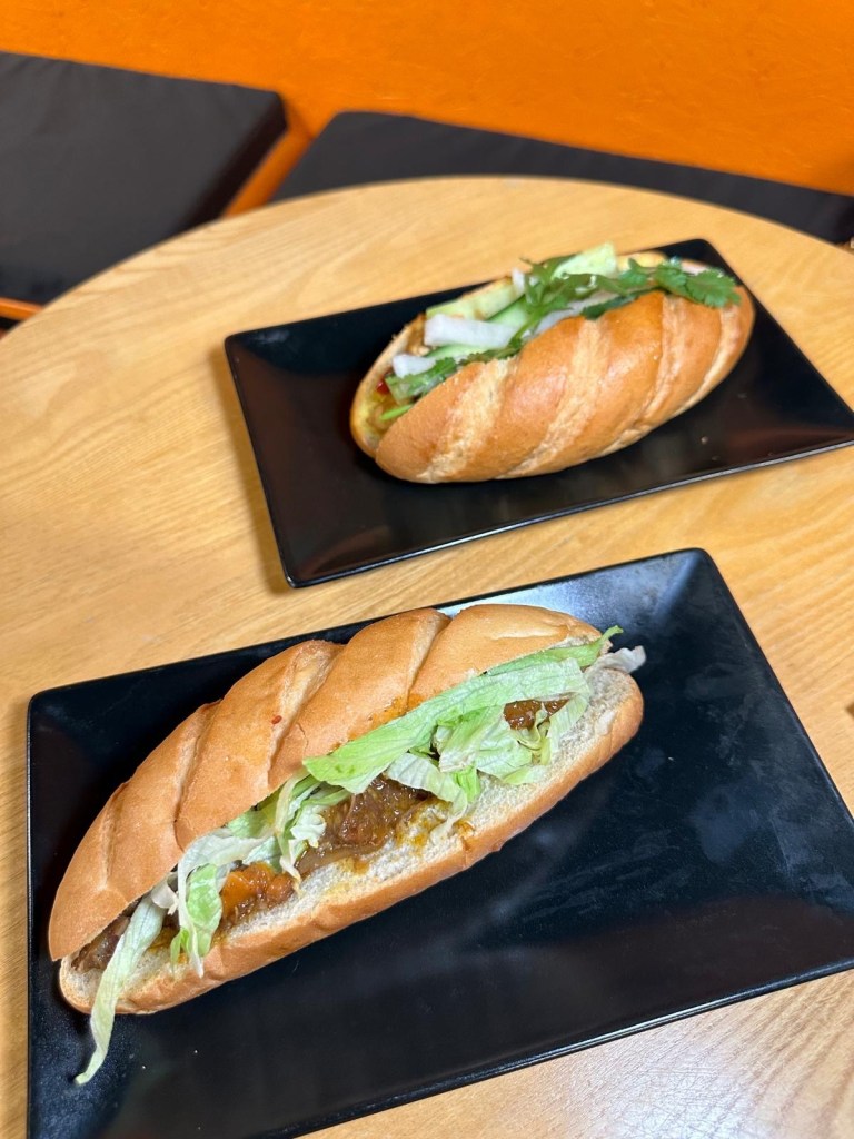 Two Vietnamese bánh mì sandwiches from Ngon Bánh Mì Newcastle, one filled with slow-cooked beef stew and the other with fragrant curry chicken.