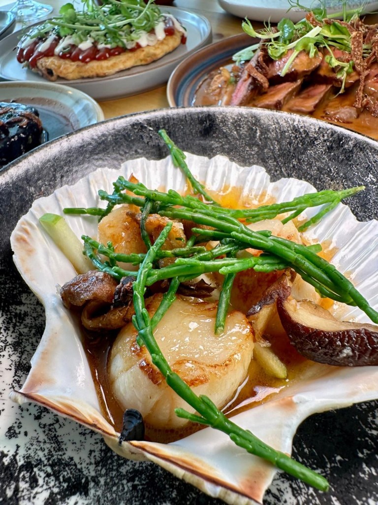 Seared scallops with celeriac purée, crispy mushrooms, and chicken butter served on a small plate at Isla Durham.