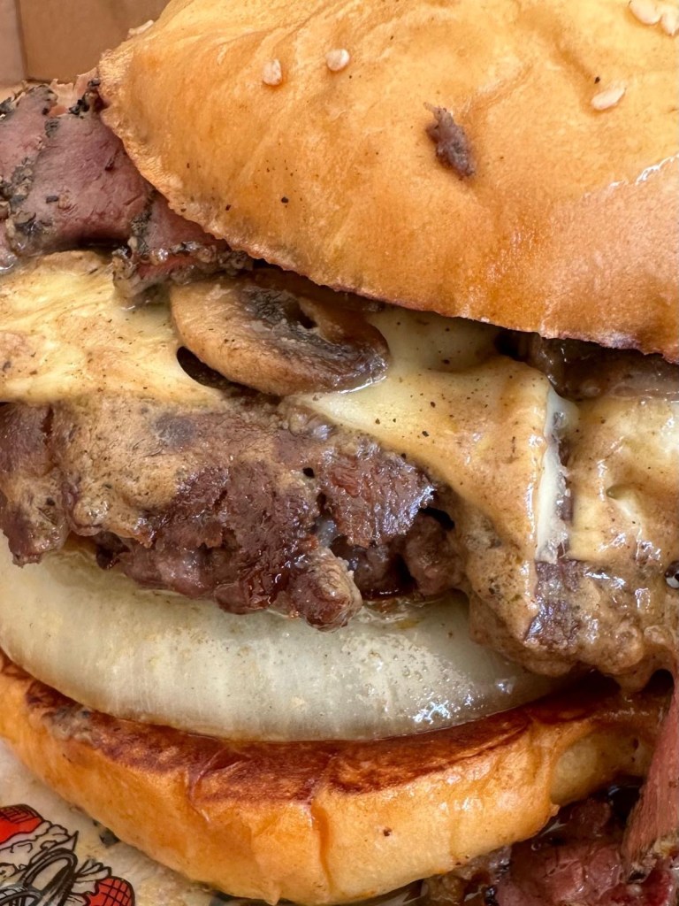 Close-up of a juicy smash burger from Friez&Burgz Newcastle with melted cheese and fresh toppings.