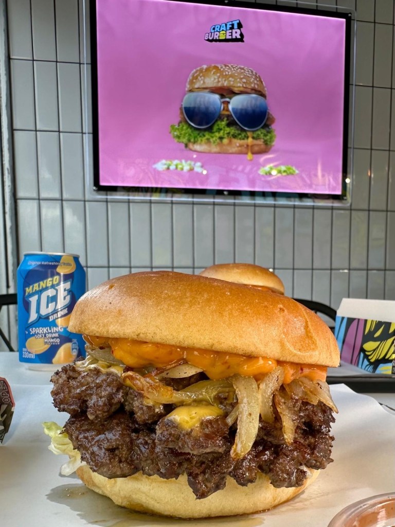 Stacked gourmet burger with fries at Burger Drop Newcastle