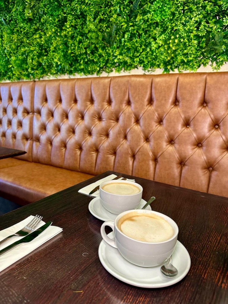 Two coffees served at Olive Kitchen Newcastle brunch café table.