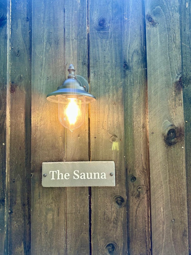 Finnish-style sauna with sundeck, loungers, and cold shower at Hewn Yorkshire.