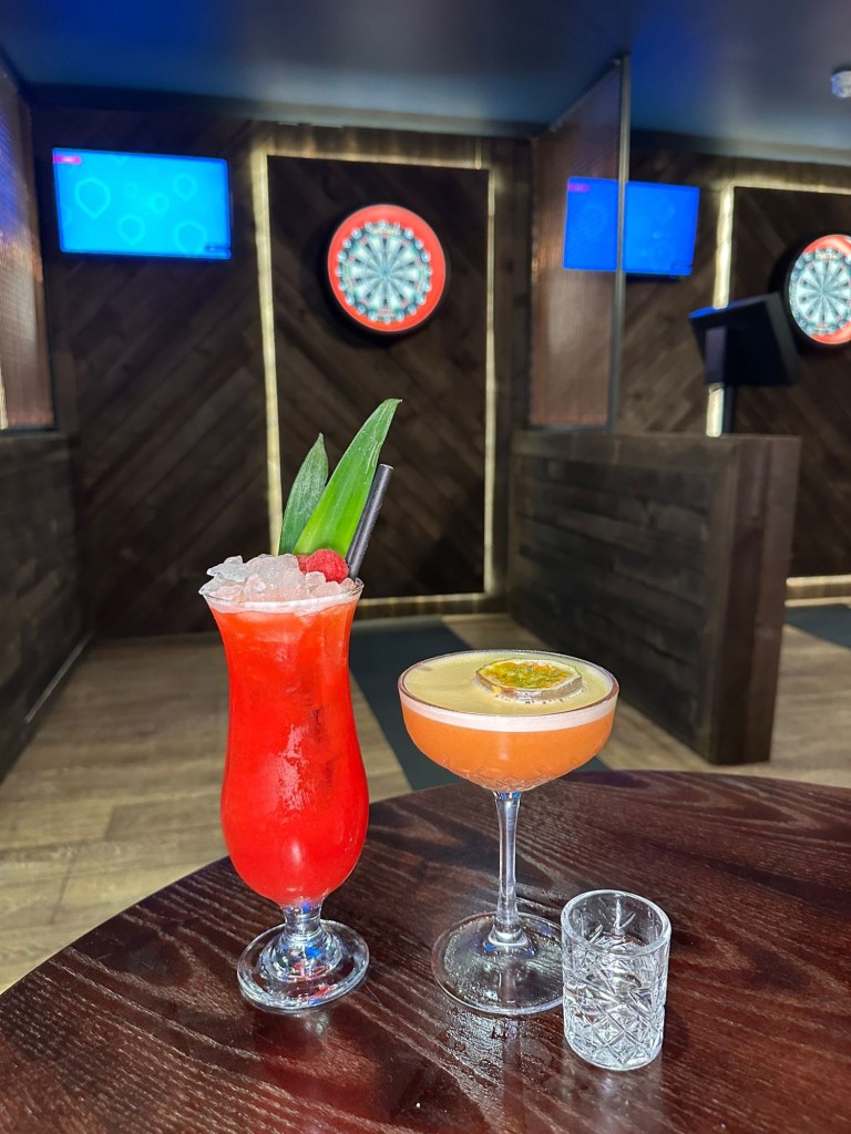 A mix of cocktails and mocktails from Bullseye Social Darts in Jesmond, including the Hollywood cocktail and alcohol-free options like Talking About Bruno and Summer Breeze — bright, refreshing and ideal for a casual night out.