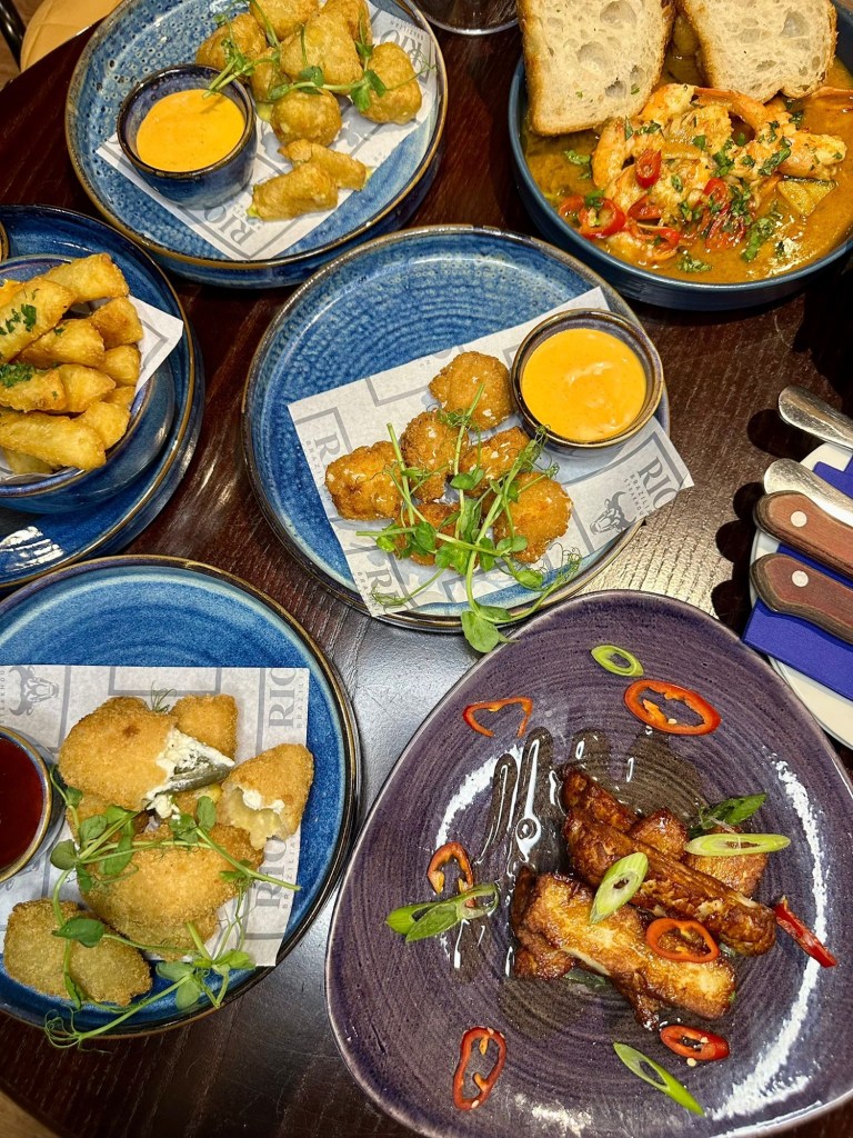 Selection of small plates at Bullseye Social Darts in Jesmond including chilli and cheese bites, mac and cheese bites, jalapeño poppers, hot honey halloumi, sautéed king prawns with focaccia, crispy yuca fries and truffle fries.
