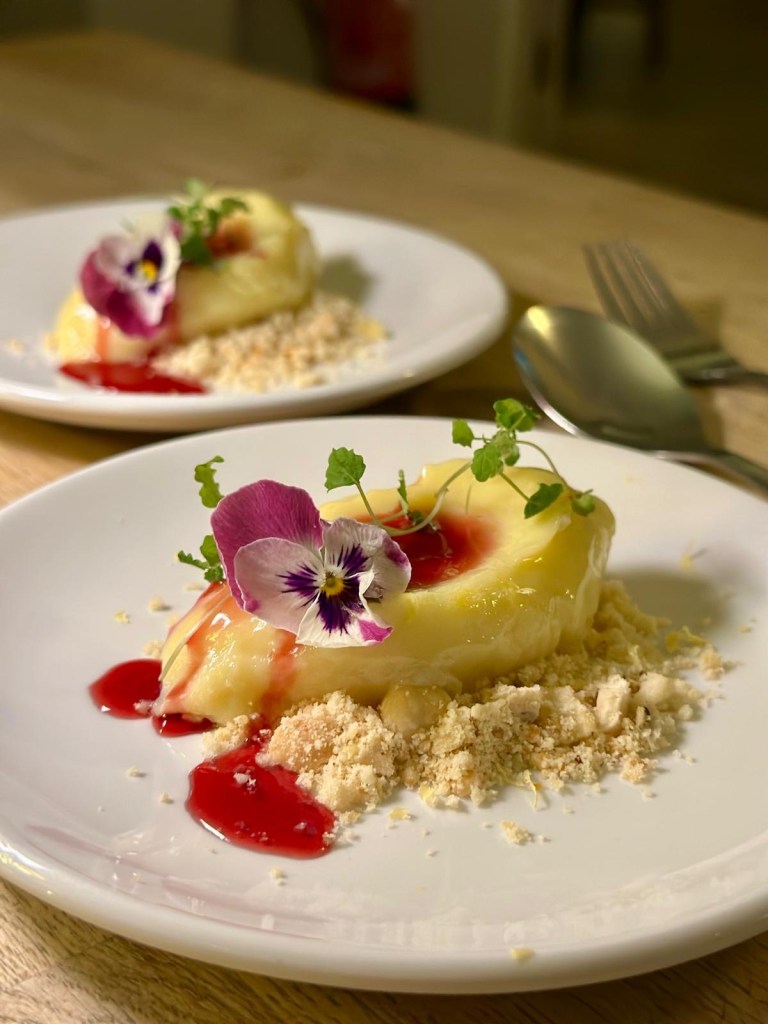 Hibiscus and white chocolate dessert, floral garnish, plated elegantly.