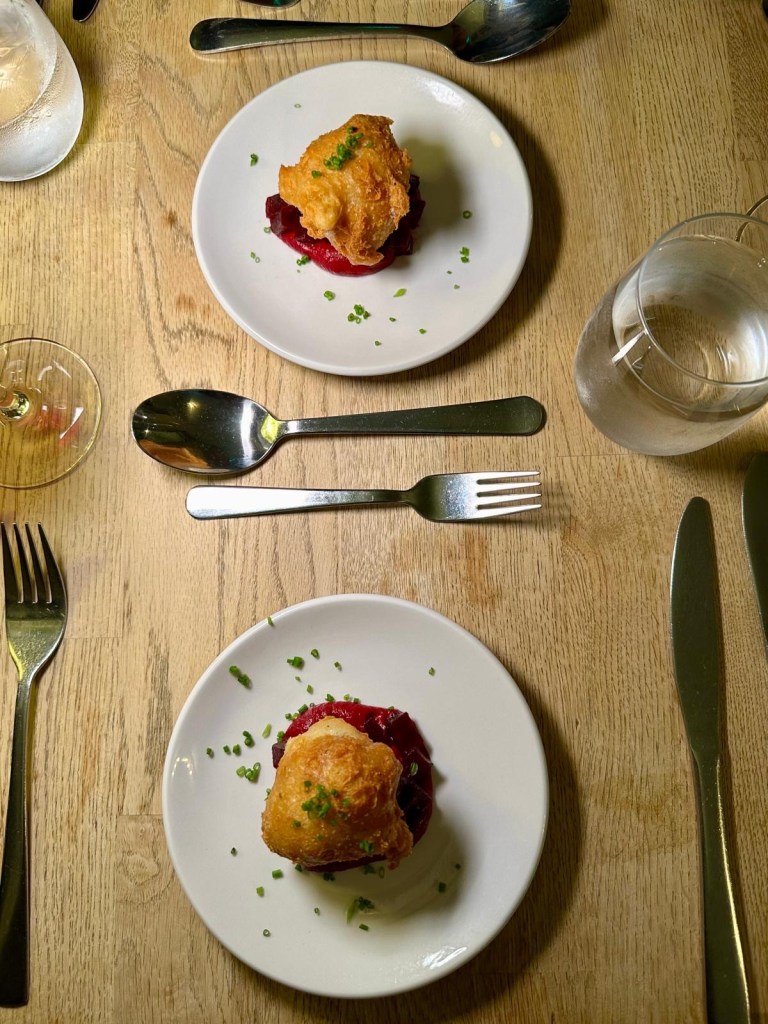 Blue cheese beignet with roasted beetroot and microgreens on a white plate
