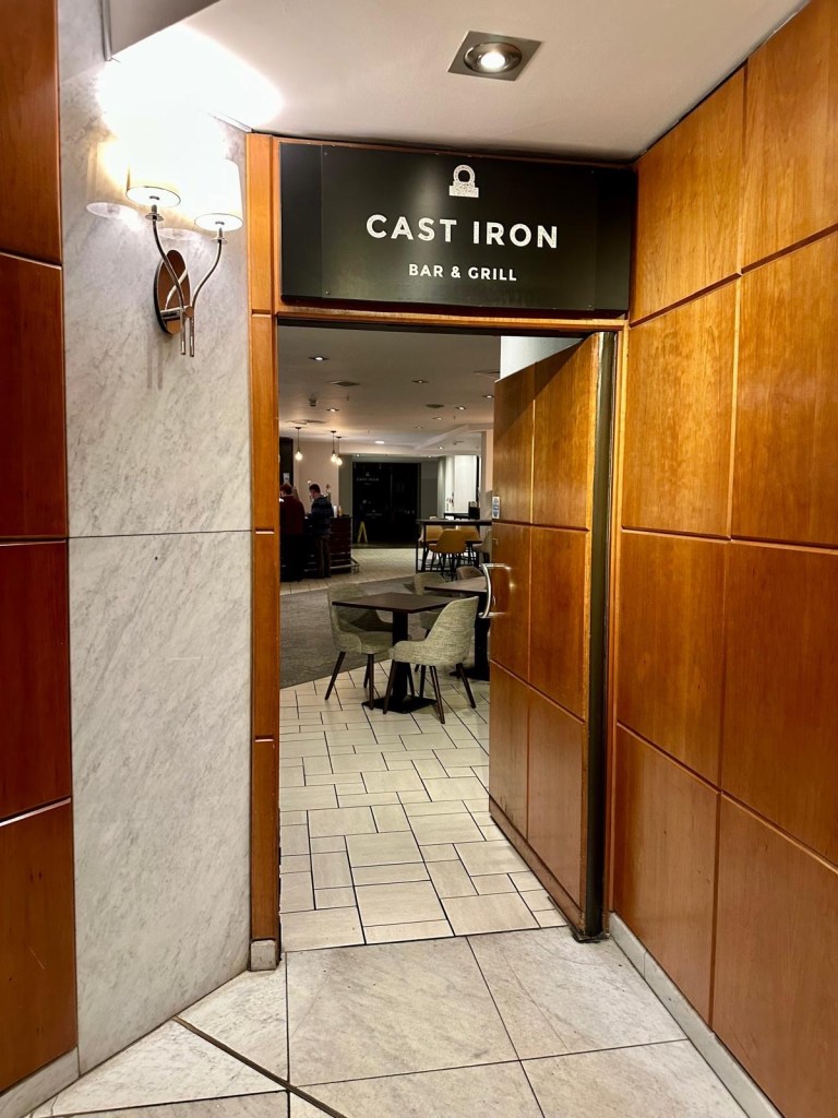 Entrance door of Cast Iron restaurant featuring the signature cleaver logo and bold branding.