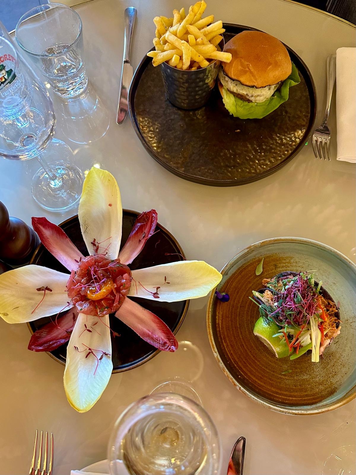 Tuna tartare, hot honey chicken burger, and cucumber watermelon salad on a table at Victors Newcastle
