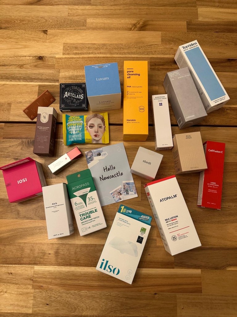 K-beauty haul from Pure Seoul displayed on a table at home, featuring skincare, makeup and sheet masks from Korean beauty brands.