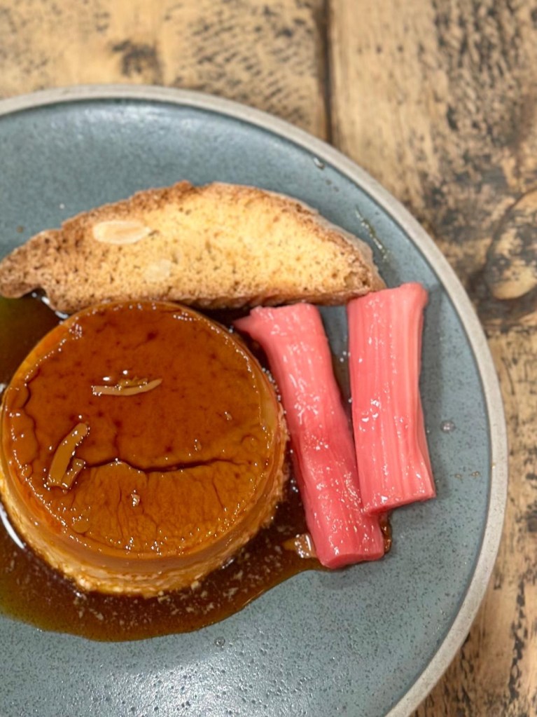 Crème caramel with poached rhubarb, stem ginger and almond biscotti at Hinnies Whitley Bay