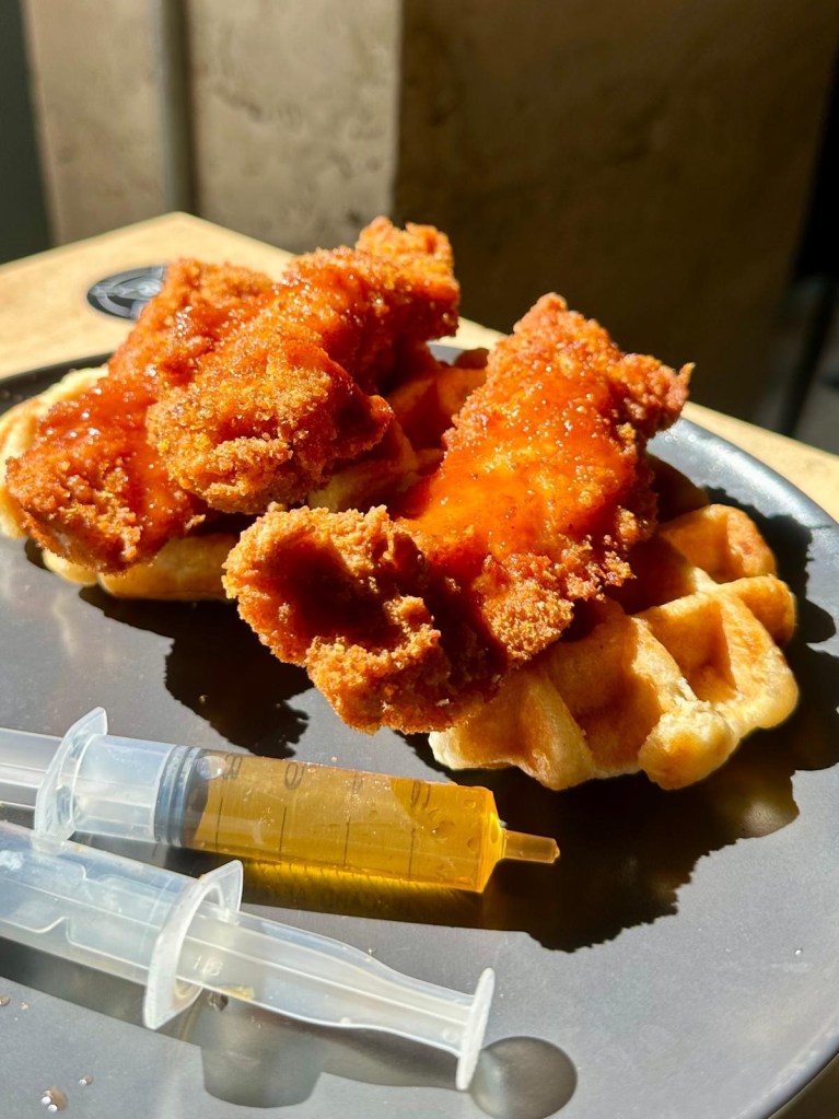 Chicken and waffles with maple syrup and honey buffalo sauce at The Dispensary Newcastle